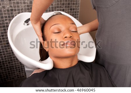 a woman gets her hair washed before getting a cut