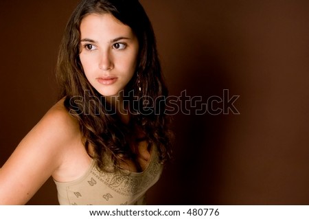 A beautiful young woman looks into the light as her shadow is cast on the brown background