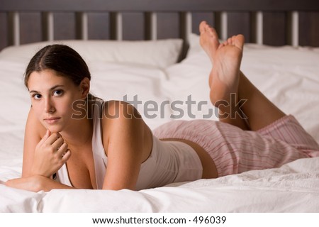 A naturally beautiful young woman lies on a kingsize bed in her pyjamas