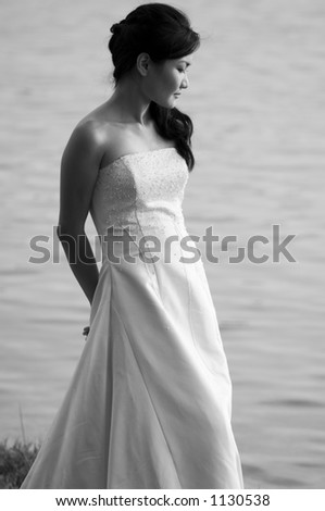 A black and white shot of a beautiful asian bride shot outdoors by a lake