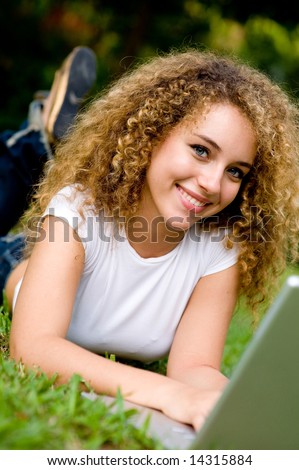 An attractive female student working on laptop in the park