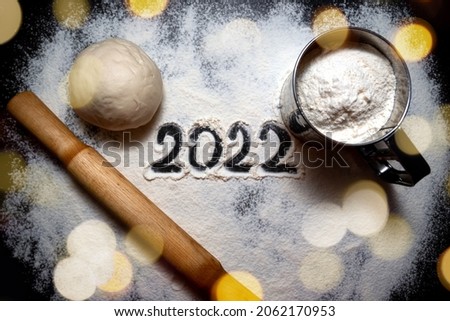 Baking flour and number 2022 on blackboard. Top view. rolling pin, flour and shape new year.New year ornament food background. Home made.