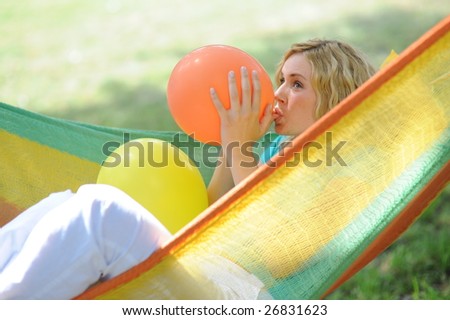 Young woman blowing up orange balloon