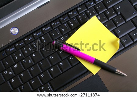 yellow note paper and pen on laptop