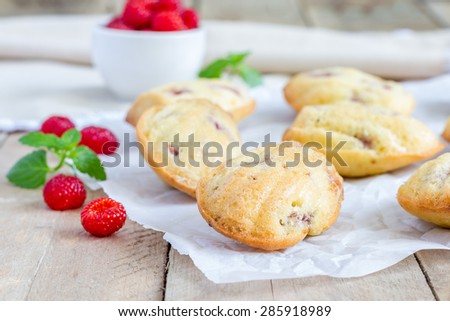 Madeleines cookie with raspberry on parchment paper, closeup