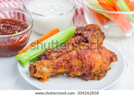 Roasted chicken served with celery and carrot sticks, blue cheese dressing and hot sauce