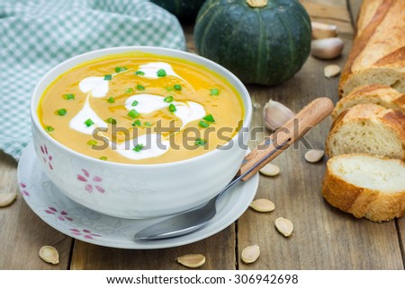 Pumpkin soup with sour cream on a wooden table