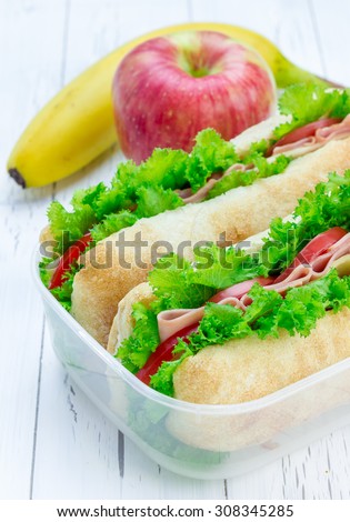 Lunch box with ciabatta bread sandwiches, apple, banana and orange juice
