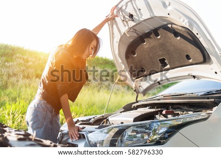 A woman checking car's battery