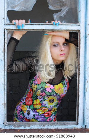 sexual blonde peers into old broken window