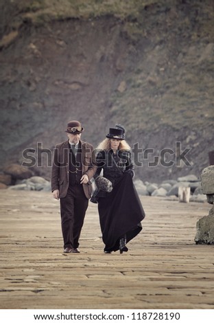 WHITBY, UK - NOV 4: A man and woman stroll along the promenade in Victorian clothing celebrating the famous Goff Weekend at Whitby, England on November 4, 2012.