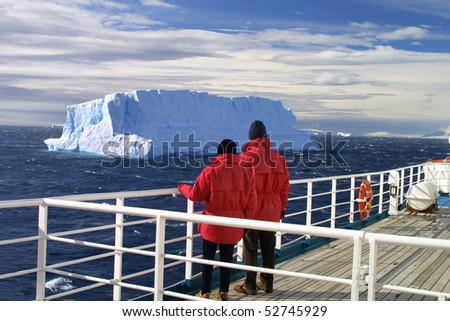 Cruise ship passengers looking at a beautiful iceberg at Antarctica