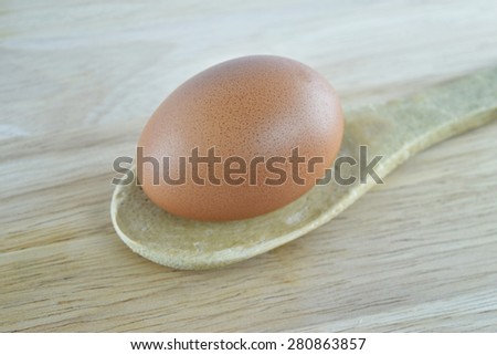 Egg in wooden spoon on wooden background