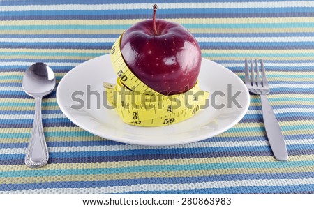 Red apples, measuring tape with Flatware in dish on napery concept  for healthy diet and body weight control.