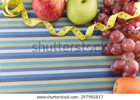 Red apple, green apple, carrot, grape and yellow measuring tape concept for healthy diet and body weight control.