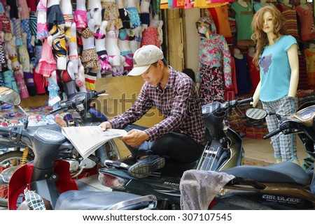 Hanoi, Vietnam - Aug 9, 2015:  Unidentified man reading newspapers on the street of Hanoi City, Viet Nam at Aug 9, 2015. Hanoi is the capital of Vietnam.