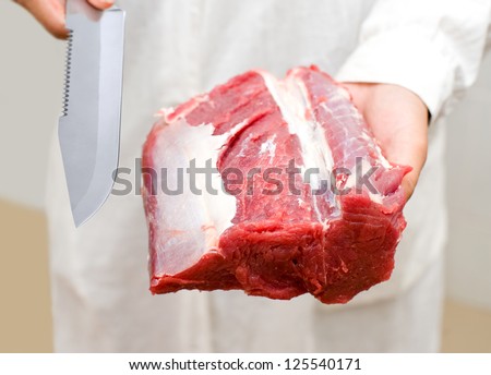 piece of fresh meat and knife in butchers hands