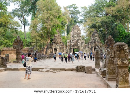 ANGKOR, CAMBODIA - FEB 21, 2013: Unidentified tourists watch around Angkor complex. About 20 thousand tourists visit the famous Angkor Khmer complex every day.