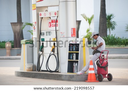 SIEM REAP, CAMBODIA - JUNE 29, 2014: An unidentified worker stands counting money at an empty petrol station. Petrol is not cheap in Cambodia - about 1.46 US dollars for 1 litre of petrol 95.