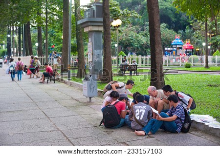 HO CHI MINH, VIETNAM - AUGUST 9, 2014: An unidentified Caucasian man teaches English to unidentified Vietnamese students in the park in Pham Ngu Lao Street.