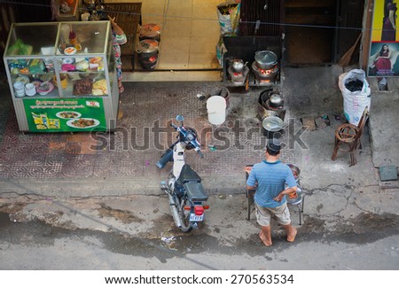 PHNOM PENH, CAMBODIA - JULY 4, 2014: An unidentified man grills meat at a local street cafe in Street 125 (Sangkat Veal Vong Street).