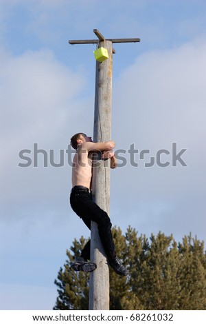 ULAN-UDE, RUSSIA - FEBRUARY 28: There are lots of public funs on the last day of the Pancake festival. The half-naked man climbs up a waxed pole to get a prize, February, 28, 2009, Ulan-Ude, Russia.