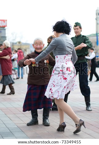 ULAN-UDE, RUSSIA - MAY 9: An unidentified old woman veteran of WWII dances with a young unidentified woman during annual Victory Day on May, 9, 2010 in Ulan-Ude, Buryatia, Russia.