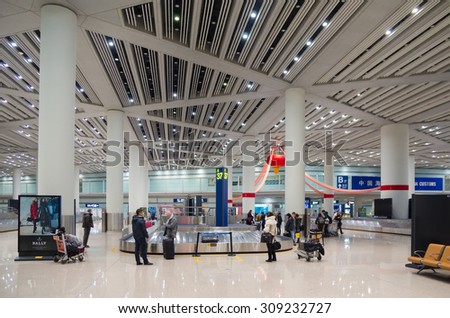 BEIJING - FEB 16, 2013: Unidentified air passengers wait for their baggage at Beijing airport luggage claim area. In 2014 it was the busiest airport in the world in terms of passenger throughput.
