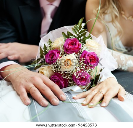 hands of the newlyweds with a bouquet