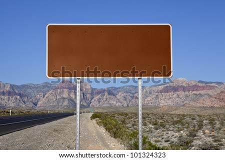 Blank brown highway sign with Nevada desert highway background.