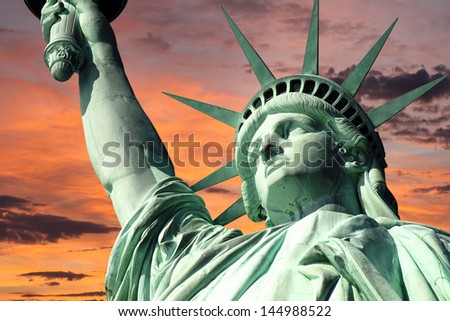 New York\'s Statue of Liberty with bright sunrise sky.