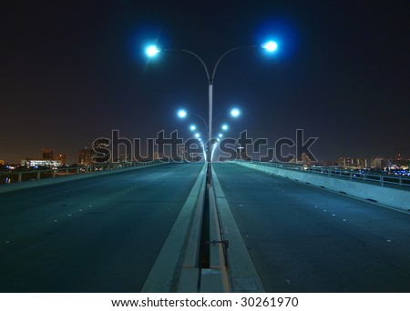 Empty bridge, towers and street lights at night.