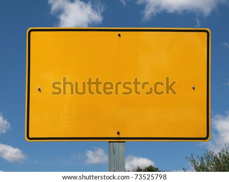 Blank reflective yellow highway message sign with puffy clouds.