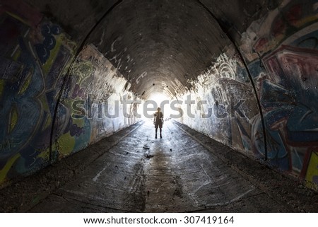 SIMI VALLEY, CALIFORNIA, USA - August 1, 2015:  Man exploring graffiti covered tunnel under the 10 lane 118 freeway near Los Angeles.