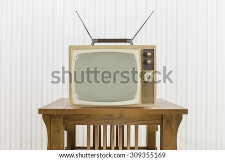 Old television with antenna on wood table.