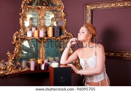 Sensual blonde girl in underwear next to a old mirror