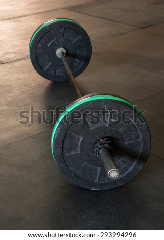 Barbell with black and green weight plates, vertical
