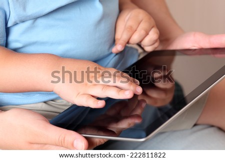 Child and mother using a digital tablet. Close-up.