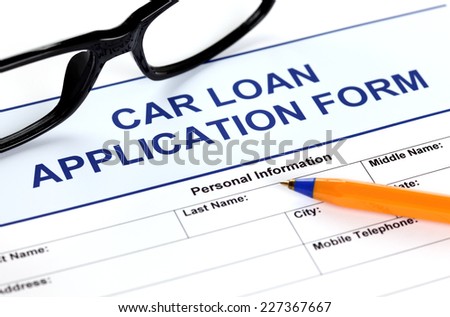 Car loan application form with glasses and ballpoint pen.