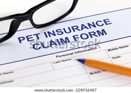 Pet insurance claim form with glasses and ballpoint pen.