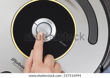 Tambov, Russian Federation - January 26, 2014 iRobot Roomba 630 Vacuum Cleaning Robot. Woman\'s finger pressing the button \
