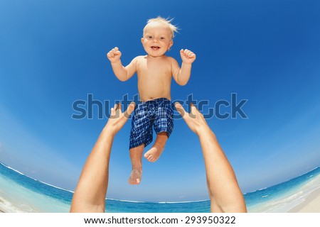 Father hands tossing up the high air joyful baby boy in on white sand sea beach. Outdoors healthy child activity, active lifestyle and having fun on family summer vacation with son on tropical island