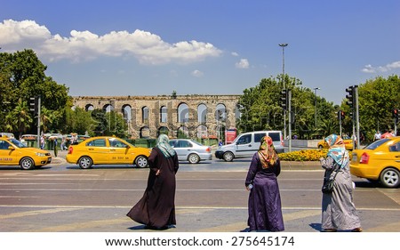 ISTANBUL - JULY 24: Muslim women are wearing religious veil and are looking at Aqueduct of Valens.