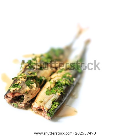 Whole baked sardines with spices, garlic and parsley on a white background. Selective Focus, Focus on the front of the baked sardines