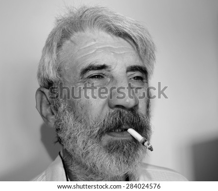 Old man smoking a cigarette. Black and white picture.