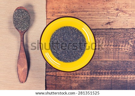 Chia jelly in a plate with spoon full of dry chia seeds on grunge wooden background. Toned.