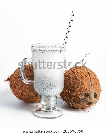 Coconut milk with chia seeds served in glass with white paper polka dot straw. Cold and refreshing drink. On white background. Selective focus.