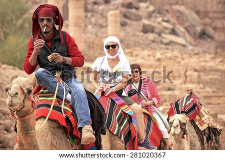 PETRA, JORDAN - NOV 29, 2013: tourists riding camels in Petra.
