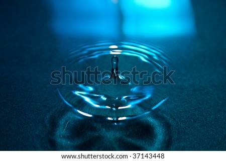A drop of water splashed into liquid surface and it\'s bouncing back. Nice reflections and wave forms.