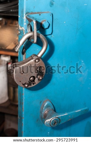 Old unlocked padlock. Hanging on the door blue box